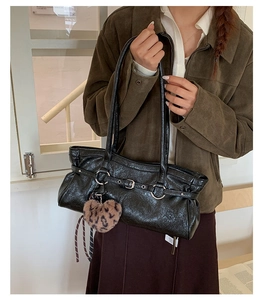 Detail of glossy black tote bag with heart leopard print charm and buckle strap