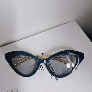 Detail view of retro cat-eye sunglasses with gold metal chain arms and dark blue frame