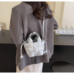 Détail du sac seau tressé argenté avec bandoulière cuir et cordon à perle