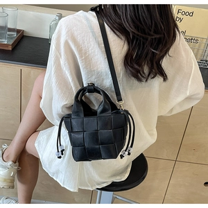 Vue lifestyle d'une femme portant un sac seau noir tressé avec détails de cordon cuir