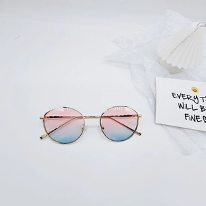 Détail de lunettes de soleil rondes en métal doré avec verres dégradés rose et bleu