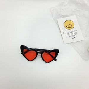 Detailed view of heart-shaped sunglasses with black frame and red lenses on white background