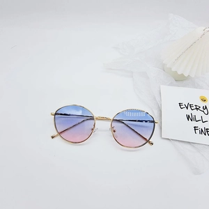 Détail des lunettes de soleil rondes en métal doré avec verres dégradés bleu-rose