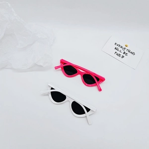 Flat lay of retro narrow cat eye sunglasses for kids in glossy pink and white frames