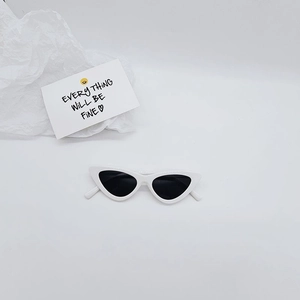Detail of white cat-eye kids sunglasses with black lenses on a minimalist background