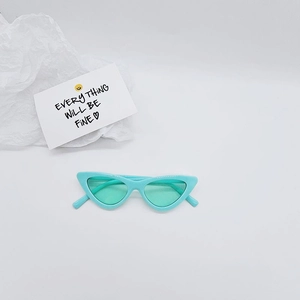Detail shot of mint green cat-eye kids sunglasses on a clean aesthetic background