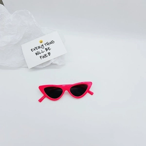 Detail view of pink cat-eye sunglasses for kids with dark lenses and retro plastic frame