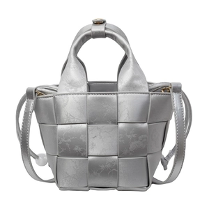Sac seau tressé argenté avec motifs floraux et poignées sur fond blanc pur