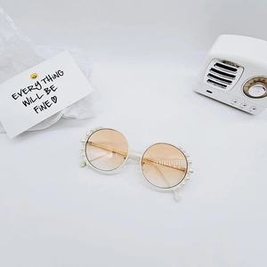 Detailed view of round frame kids sunglasses with pearl trim and gradient lenses