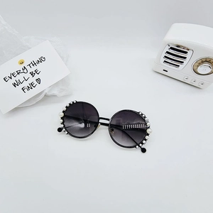 Detail of round children's sunglasses with white pearl embellishments and black frame