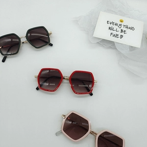 Detail of oversized hexagonal kids sunglasses in black, red and light pink colors
