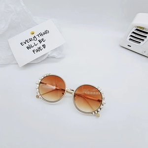 Detailed view of round metal children sunglasses with pearl trim and gradient lenses