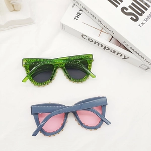 Chic cat-eye sunglasses with gold stud rivets in green and blue frames on white fabric