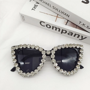 Macro detail of oversized black sunglasses with luxury crystal rhinestones on white fabric