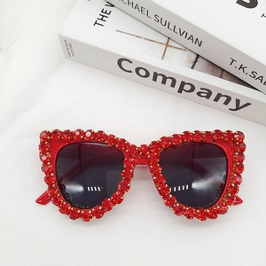 Close-up of red cat-eye sunglasses featuring hand-set crystals and dark tinted lenses