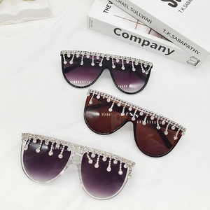 Trois lunettes de soleil oversize avec franges de cristal sur un tissu blanc doux