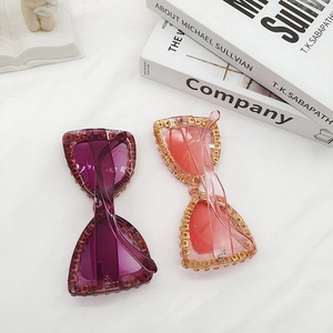 Close-up of oversized butterfly sunglasses with rhinestone frames in purple and pink
