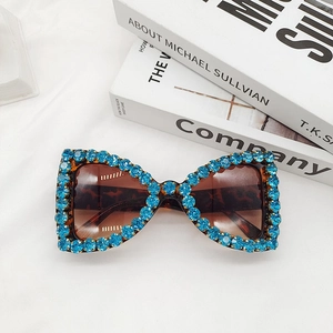 Macro shot of butterfly frame sunglasses with blue rhinestones and tortoiseshell finish