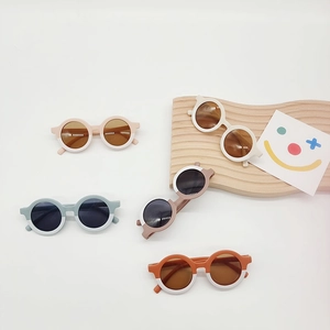 Kids round frame sunglasses in assorted colors on a wooden wave display board