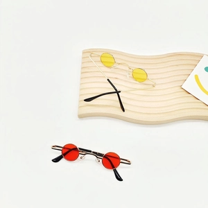 Close-up of mini round retro sunglasses with gold metal frames and colored lenses