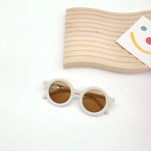 Detail view of round frame kids sunglasses with bicolor design on a white background