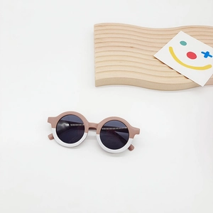 Detail of round kids sunglasses featuring a two-tone brown and white PC frame