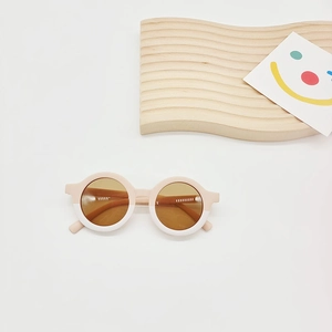 Detail of round toddler sunglasses featuring pink and white bicolor frames and brown lenses