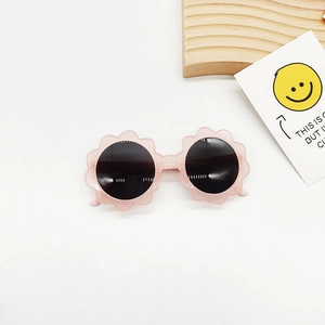 Nahaufnahme der Kinder Sonnenbrille mit rosa Blütenrahmen auf einem Wellentablett