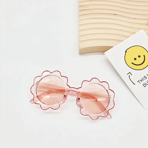 Detailansicht der pinkfarbenen Kinder-Sonnenbrille in Blumenform auf Holztablett