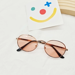 Close-up of rose gold metal sunglasses with rhinestones on the bridge and wavy temples