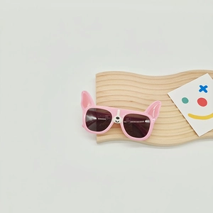 Detailed view of pink French Bulldog themed kids sunglasses on a wooden display stand