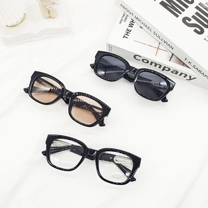 Trois lunettes de soleil carrées noires élégantes avec divers verres sur un tissu blanc