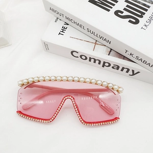 Gros plan de lunettes de soleil roses surdimensionnées avec bordure perle et strass brillants