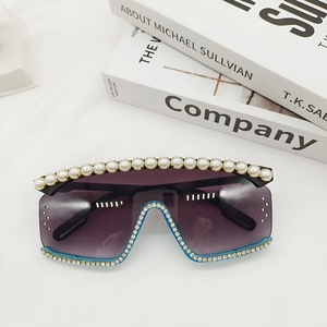 Détail de lunettes de soleil oversize avec perles blanches et cristaux sur la monture