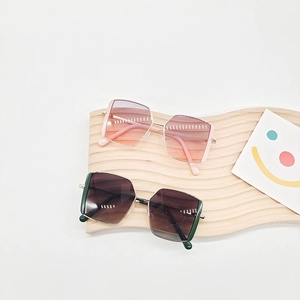 Geometrische Kinder-Sonnenbrille mit Verlaufsgläsern und Metallrahmen auf Holztablett