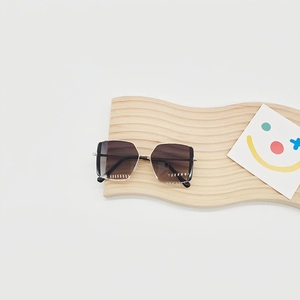 Detailansicht der Retro-Metall-Sonnenbrille mit braunem Farbverlauf auf Holzständer