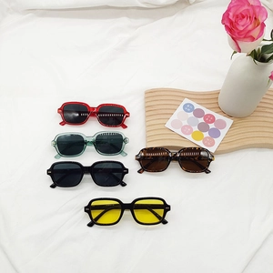 Lunettes de soleil carrées rétro en plusieurs couleurs sur un fond en tissu blanc