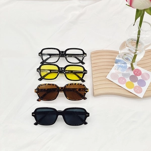 Lunettes de soleil rétro carrées en quatre couleurs avec rivets dorés sur tissu blanc