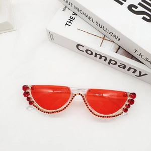 Macro shot of semi-rimless sunglasses with vibrant red lenses and sparkling red rhinestones