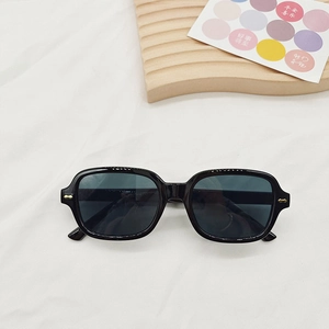 Vue détaillée des lunettes de soleil carrées noires avec nœuds décoratifs dorés sur les branches