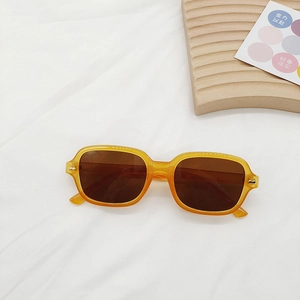 Vue à plat de lunettes de soleil carrées orange vintage sur tissu blanc épuré