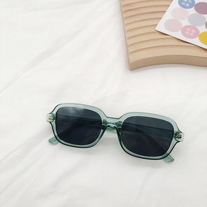 Gros plan de lunettes de soleil carrées vert foncé rétro avec rivets sur tissu blanc