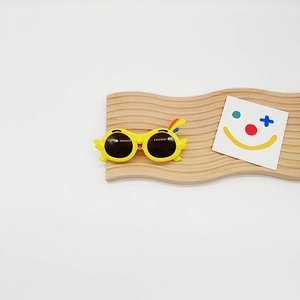 Detail of yellow parrot cartoon sunglasses for kids with colorful feather accents