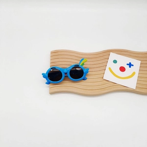 Close-up of blue parrot-shaped kids sunglasses with decorative wings and colorful feathers
