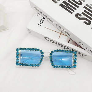 Detail of blue rhinestone rectangular sunglasses with crystal frames on a clean white fabric
