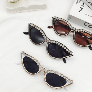 Détail de lunettes de soleil œil de chat strassées avec montures noires, blanches et écaillées