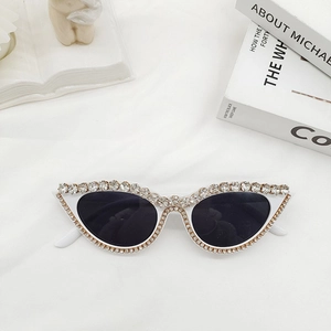 Détail de lunettes de soleil œil-de-chat blanches avec strass et verres océan