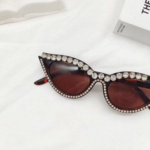 Gros plan de lunettes œil-de-chat avec de grands strass et verres marrons sur tissu