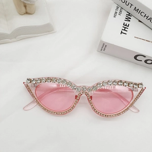 Détail de lunettes de soleil œil-de-chat roses avec strass sur fond blanc texturé