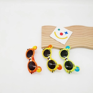 Détail de trois lunettes de soleil pour enfants avec oreilles d'ours en orange et jaune